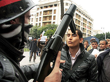 A riot policeman faces off with a protester during a demonstration in downtown Tunis