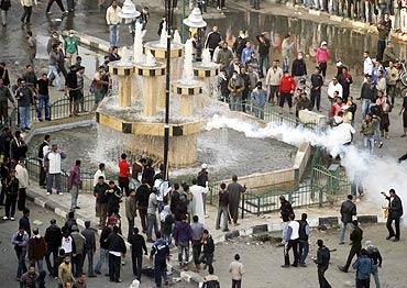 Anti-government demonstrators watch as tear gas is fired by police in an attempt to disperse them  in the port city of Suez