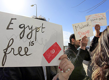 People hold signs during a protest in front of the Egyptian embassy in Tunis