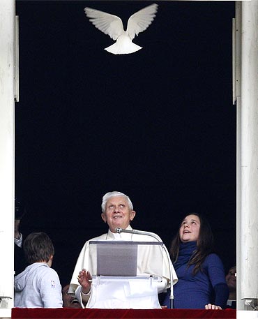 Pope Benedict XVI looks at a dove as it flies back in the room