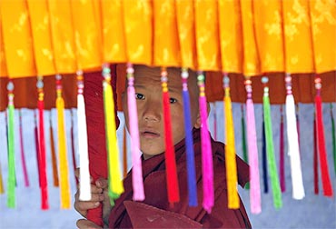 A young monk holds a traditional parasol as he waits for the arrival of Dalai Lama in Pemayangtse monastery in Sikkim
