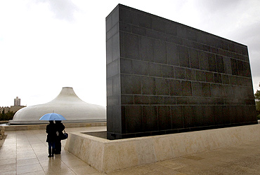 People stand under an umbrella in front of the Shrine of the Book, which houses the Dead Sea Scrolls and other ancient manuscripts, at the Israel Museum in Jerusalem.