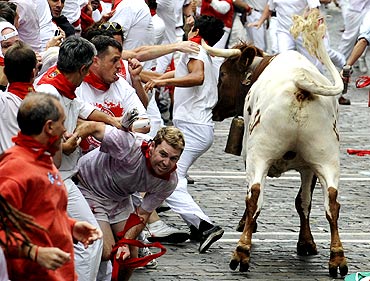 A steer pushes a reveller with his horn during the first bull run