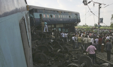 People watch as rescue personnel search for survivors in the mangled carriages of Kalka Mail