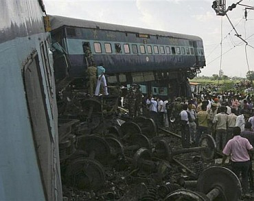 People watch as rescue personnel search the mangled carriages of the Kalka Mail train which derailed near Fatehpur