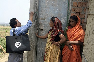 A census official (L) marks a house after collecting details from a village resident