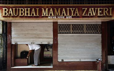 A businessman locks his shop at Zaveri Bazaar after the blasts