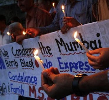 People hold candles during a prayer ceremony for the victims of Wednesday's triple explosions in Mumbai