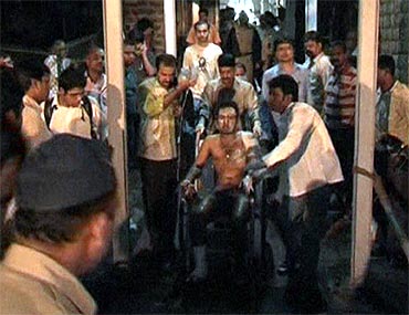 A victim is taken away on a wheelchair at a blast site