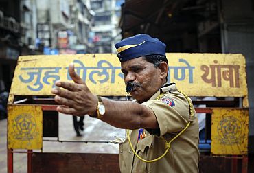 A policeman whistles and gestures to onlookers at Zaveri Bazaar in Mumbai