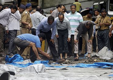 A man moves debris from the blast site at Zaveri Bazaar in Mumbai