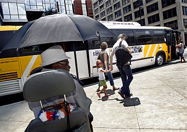 Tommy Fowler (Left) shields himself from the sun as he waits to board a bus during a prolonged heat wave in Dallas, Texas