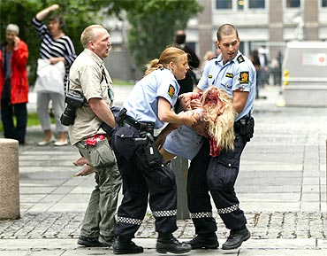 Policemen evacuate an injured woman after a powerful explosion rocked central Oslo