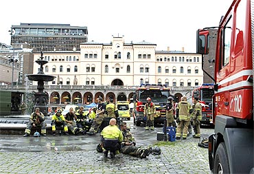 Rescue workers gather near the site of a powerful explosion that rocked central Oslo