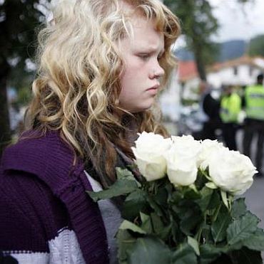A girl lays flowers in front of a hotel where relatives and survivors of a shooting rampage on nearby Utoeya island gather after a memorial service in Sundvollen