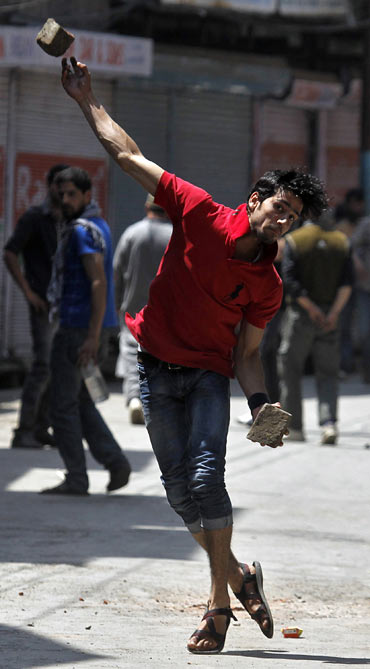 A Kashmiri youth throws a piece of brick towards the police during a clash in Srinagar