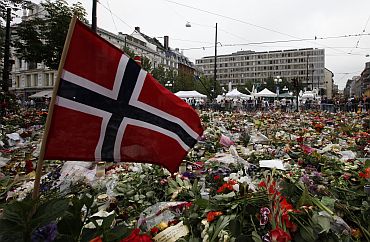 Norwegian flag is placed in a sea of flowers and candles which are placed in memory of those killed in bomb and shooting attack in front of Oslo Cathedral