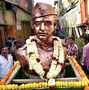 People stand beside a statue of former leader Subhas Chandra Bose to commemorate his birthday in Kolkata