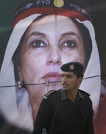 A policeman walks past an image of Benazir Bhutto on her death anniversary