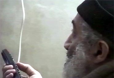 Osama bin Laden is shown holding a remote while watching himself on television in this video frame grab released by the Pentagon