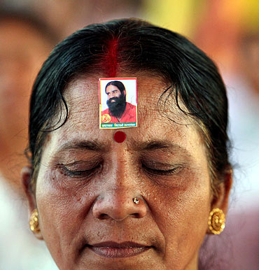 A supporter wears an image of Swami Ramdev while listening to his address at the Ramlila Grounds
