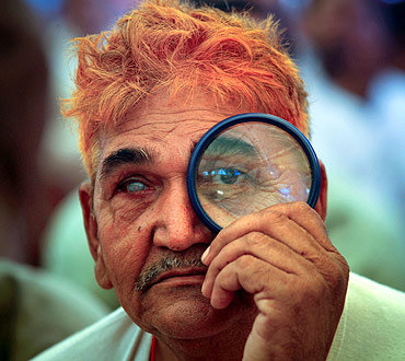 A supporter of Swami Ramdev uses a magnifying glass to watch his address