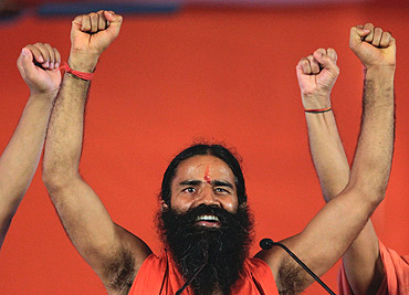 Swami Ramdev raises his hands with supporters at the Ramlila Grounds