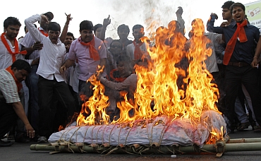 BJP supporters shout slogans in favour of Ramdev as they burn an effigy of PM Singh