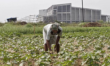 A farmer works a crop next to the closed Tata Motors Nano car factory in Singur