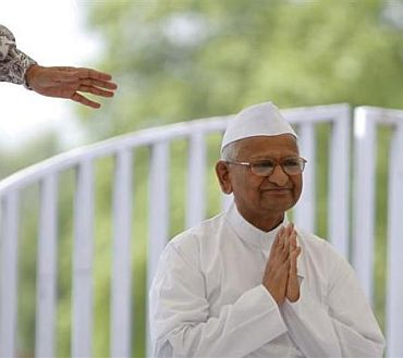 Veteran social activist Anna Hazare clasps his hands together as he greets supporters after arriving for his hunger strike at Rajghat in New Delhi