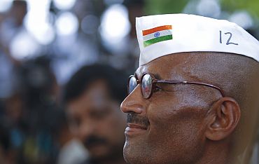 A supporter dressed as Mahatma Gandhi listens to Anna Hazare speaking during his hunger strike at Rajghat in New Delhi on Wednesday