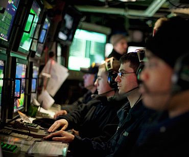 Navy sailors watch their sonar screens as they work in the control room of USS New Hampshire