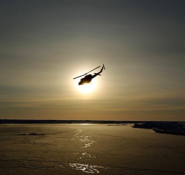 A helicopter flies over Arctic ice towards the Applied Physics Laboratory Ice Station