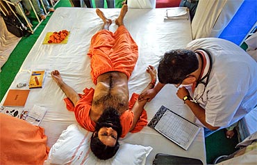 A doctor checks the pulse of Swami Ramdev