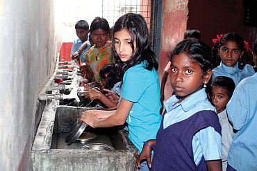 Anjali Rangaswami, 1st one washing dishes, at an Akshaya Patra-sponsored school kitchen in Bangalore