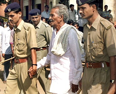 Policemen escort one of the prime suspects in the Gujarat riots case to a court in Nadiad in November 2003