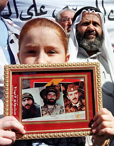 A boy holds pictures of Chechen leaders (L-R Salman Raduyev, Shamil Basayev and Dzhakhar Dudayev) during a protest in Amman