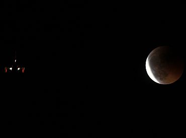 An aircraft flies as the shadow of the earth falls on the moon during a total lunar eclipse in Malaga, southern Spain