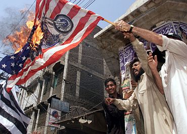 Anti-US demonstrators wave a burning American flag during a protest rally in Peshawar