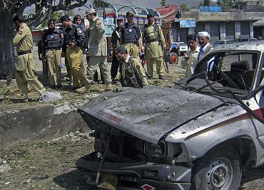Policemen and paramilitary forces stand at the scene of a suicide bomb blast in Dir, northwest Pakistan