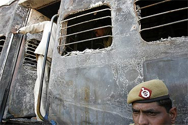 A policeman stands outside a burnt carriage of Samjhauta Express after the blast