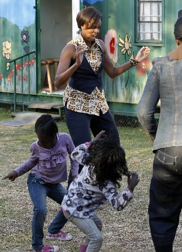 Michelle Obama dances with children as she visits the Emthonjeni Community Center in Zandspruit Township, Johannesburg