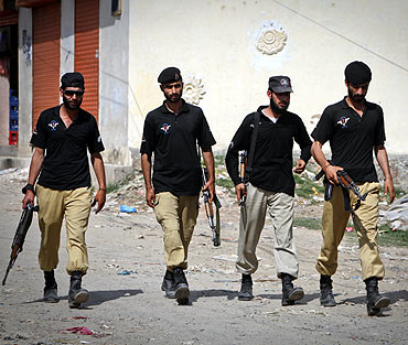Members of Pakistan's anti-terrorism squad walk past the compound where bin Laden was killed in Abbottabad