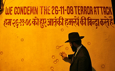 A rabbi touches a wall riddled with bullet holes in front of Nariman House, a target of the 26/11 terror strike
