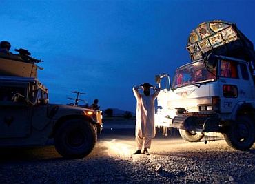 An Afghan man places his hands over his head as US soldiers search his truck for weapons near Sanjaray in Zhari district