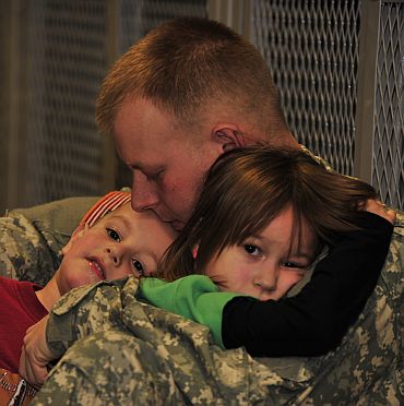 Pfc Chris Paterson, a native of Hudson, Ohio, holds his daughter Aliva and son Foster before deploying to Afghanistan from Fort Drum, New York. Paterson is an infantryman assigned to Charlie Company, 2nd Battalion, 22nd Infantry Regiment of the 10th Mountain Division's 1st Brigade Combat Team.