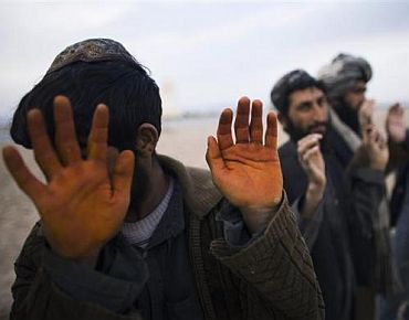 Afghan men wait to be searched at a checkpoint at Delaram district in Nimroz province