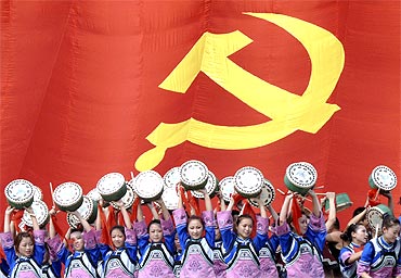 Actresses of Tujia minority dance as they sing Chinese revolutionary songs in front of a giant flag of the Communist Party of China during a performance to celebrate CPC's 90th anniversary
