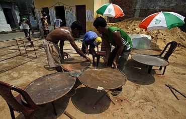 Labourers prepare metal campaign props in the shape of flowers, a symbol of the Trinamool Congress in West Bengal