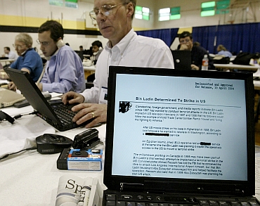 Members of the White House press corps read on their computers a Presidential daily briefing document